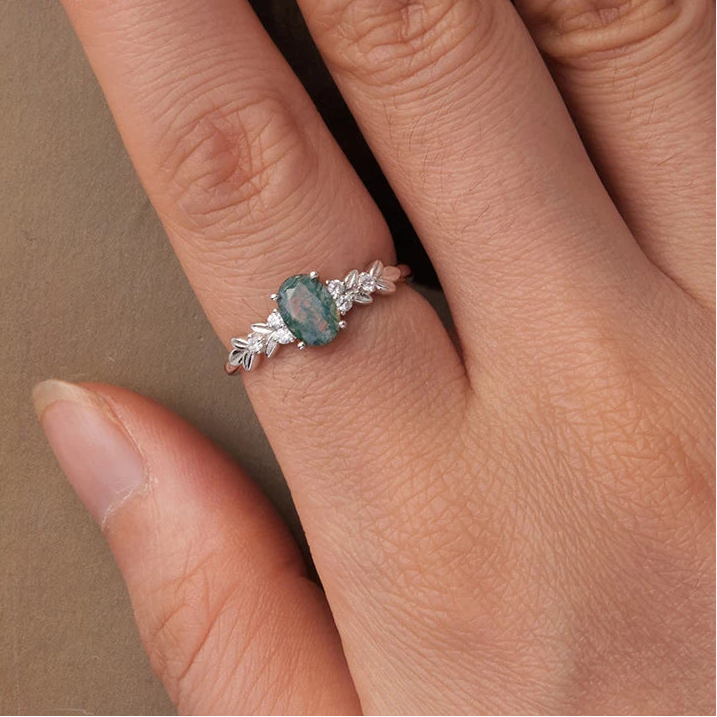 Ring with a green gemstone on a finger, brand 'PALASH' visible

