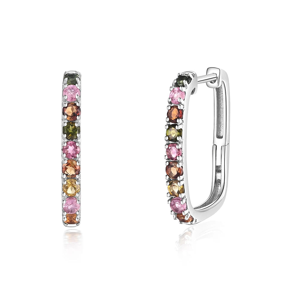 A pair of silver huggie hoop earrings with a vertical channel setting featuring multiple round-cut gemstones in pink, green, orange, and yellow, shown on a white background 
