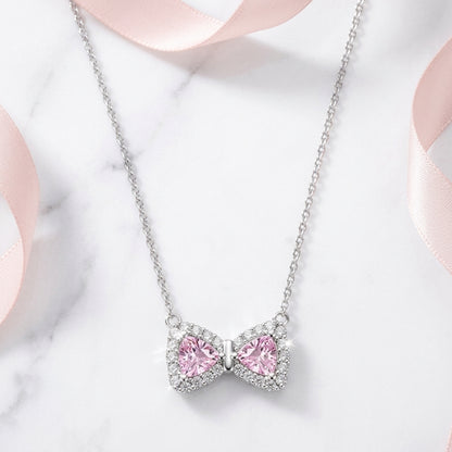 Necklace with a pink bow-shaped pendant on a light background